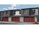 Exterior of modern townhomes showcasing brick-red garage doors and updated outdoor lighting at 9451 Calm Stream Ave # Lot 81, Las Vegas, NV 89178