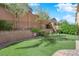 This landscaped backyard has a putting green, mature trees, and a brick retaining wall for privacy and beauty at 10457 Raining Sky St, Las Vegas, NV 89178