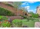 Landscaped backyard featuring a putting green, mature trees, and a brick retaining wall, offering privacy and charm at 10457 Raining Sky St, Las Vegas, NV 89178