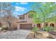 Charming two-story home featuring a well-manicured lawn, mature trees, and a two-car garage, showcasing curb appeal at 10457 Raining Sky St, Las Vegas, NV 89178