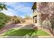 Desert landscaped backyard with artificial turf, brick pavers, mature landscaping, and covered porch at 1053 Hickory Park St, Las Vegas, NV 89138