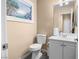 Well-lit half bathroom features a toilet, a vanity with storage, and a framed floral print on the wall at 1495 Le Luberon Ct, Las Vegas, NV 89123