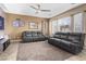 Spacious living room with tile floors, two dark sofas, a ceiling fan, and plenty of natural light at 1495 Le Luberon Ct, Las Vegas, NV 89123