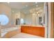 Bright bathroom featuring a soaking tub, unique round windows, and a double vanity with wood cabinets at 2877 Paradise Rd # 104, Las Vegas, NV 89109