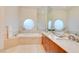 Bright bathroom featuring a soaking tub, dual sinks, and round frosted windows, creating a spa-like atmosphere at 2877 Paradise Rd # 104, Las Vegas, NV 89109