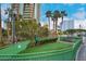 A dog park with palm trees, a bench, green fencing, and artificial turf for a clean, pet-friendly environment at 2877 Paradise Rd # 104, Las Vegas, NV 89109