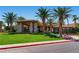 A view of the clubhouse featuring stone accents, professional landscaping and mature palm trees at 296 Brushy Creek Ave, Las Vegas, NV 89148