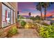 A serene outdoor patio with tile flooring, lush landscaping, and a glimpse of a colorful sunset sky at 296 Brushy Creek Ave, Las Vegas, NV 89148