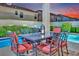 A patio dining table is situated next to a small pool and manicured greenery in the backyard at 296 Brushy Creek Ave, Las Vegas, NV 89148
