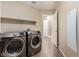 Spacious laundry room with modern washer and dryer, shelving, and tile flooring at 3305 Alcudia Bay Ave, Las Vegas, NV 89141