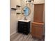 This bathroom includes a black vanity, round mirror, floating shelves and wood-look vinyl flooring at 3365 Badura Ave, Las Vegas, NV 89118