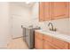 Laundry room with utility sink, counter space, wooden cabinets, and modern appliances at 3365 Badura Ave, Las Vegas, NV 89118