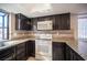 Well-lit kitchen features dark cabinets, granite countertops, and modern white appliances, enhanced by natural light at 3369 Milenko Dr, Las Vegas, NV 89121