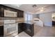 Open concept kitchen with dark wood cabinets, granite counters, white range, and connecting dining area at 3369 Milenko Dr, Las Vegas, NV 89121