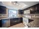 Charming kitchen featuring dark cabinets, granite counters, stainless dishwasher, and white appliances at 3369 Milenko Dr, Las Vegas, NV 89121