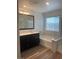 Bright bathroom featuring a tub, shower, wood-look floors, dark cabinets and natural light at 5773 Fresh Fields Ct, Las Vegas, NV 89118