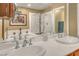 A primary bath offers double sinks, neutral colors, and a separate glass shower for a luxurious experience at 64 Strada Principale # 307, Henderson, NV 89011