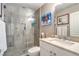 Bright bathroom featuring a walk-in shower with glass door, neutral stone tile, and a modern vanity with artful decor at 7131 Mission Hills Dr, Las Vegas, NV 89113