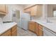 Bright kitchen featuring stainless steel appliances, wood cabinetry, and adjacent laundry room at 7163 S Durango Dr # 108, Las Vegas, NV 89113