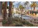 Community pool area surrounded by lush landscaping, tables and chairs, and multiple story residential buildings at 7163 S Durango Dr # 108, Las Vegas, NV 89113