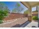Cozy backyard patio with low-maintenance gravel and block wall surrounded by trees and bushes at 8348 Mokena Ave, Las Vegas, NV 89178