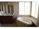 Relaxing Primary bath with a soaking tub, large mirror, and window at 8348 Mokena Ave, Las Vegas, NV 89178