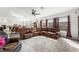 Spacious living room with a ceiling fan, large windows, and a leather sofa perfect for relaxation at 8415 Iron Heart Ln, Las Vegas, NV 89113