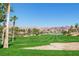 A lush green golf course with a sand trap, palm trees, and mountain views in the background at 1026 Via Saint Andrea Pl, Henderson, NV 89011
