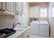 Bright laundry room with sink, white cabinets, and modern washer and dryer at 10640 Mission Lakes Ave, Las Vegas, NV 89134