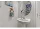 Cozy powder room with a modern pedestal sink, round mirror, and unique blue and white wall accents at 1131 Orange Meadow St, Las Vegas, NV 89142