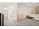Cozy carpeted bedroom featuring a window with blinds, neutral tones, and a glimpse of adjoining spaces at 11676 Midnight Melody Ave, Las Vegas, NV 89138