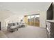 Bright, open living room with plush carpet, stylish sofa, and large sliding glass doors to the outside at 11676 Midnight Melody Ave, Las Vegas, NV 89138