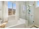 Bright bathroom with a bathtub and shower, white cabinets, and tile at 11878 Albissola Ave, Las Vegas, NV 89138