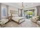 This main bedroom has natural lighting, a chandelier, a patterned rug, a comfortable seating area, and backyard access at 11878 Albissola Ave, Las Vegas, NV 89138