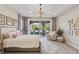 A light-filled main bedroom with chandelier lighting, plush rug, seating area, and backyard view through glass doors at 11878 Albissola Ave, Las Vegas, NV 89138