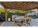 Outdoor kitchen and dining area under a pergola, perfect for entertaining and enjoying the outdoors at 11878 Albissola Ave, Las Vegas, NV 89138