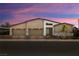 Contemporary home featuring a three-car garage and modern design with stone accents and desert landscaping at sunset at 135 Barnett Crest Ct, Henderson, NV 89015