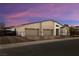 Contemporary home featuring a three-car garage and modern design with stone accents and desert landscaping at sunset at 135 Barnett Crest Ct, Henderson, NV 89015