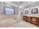 Bright bathroom featuring double vanities, a soaking tub, tiled floors and framed mirrors and a glass enclosed shower at 1983 Songbird Ct, Henderson, NV 89012