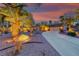 Desert landscaped home with a long driveway lined with palm trees against a colorful sunset at 1983 Songbird Ct, Henderson, NV 89012