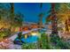 Backyard swimming pool with a rock waterfall, lush landscaping, and a tiki bar at 1983 Songbird Ct, Henderson, NV 89012