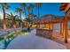 Backyard swimming pool with a rock waterfall, lush landscaping, and a tiki bar at 1983 Songbird Ct, Henderson, NV 89012