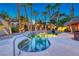 Backyard swimming pool with a rock waterfall, lush landscaping, and lighting at 1983 Songbird Ct, Henderson, NV 89012