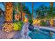Backyard swimming pool with a rock waterfall, lush landscaping, and lighting at 1983 Songbird Ct, Henderson, NV 89012