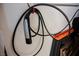 This image shows a black Tesla charger with a silver handle hung from a red hook at 2306 Valley Cottage Ave, Henderson, NV 89052