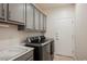 Functional laundry area with gray cabinets, modern washer and dryer, and neutral walls at 2306 Valley Cottage Ave, Henderson, NV 89052