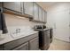 A convenient laundry room features gray cabinets, a sink, and stainless steel washer and dryer at 2306 Valley Cottage Ave, Henderson, NV 89052