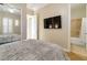Bedroom featuring a mirror, large television, and view into a bathroom with a tiled shower at 2665 Chateau Clermont St, Henderson, NV 89044