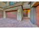 Welcoming home exterior with a three-car garage, brick driveway, and covered entryway at 28 Vista Outlook St, Henderson, NV 89011