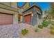 Charming home exterior with three-car garage, beautiful brick driveway, and desert-style landscaping at 28 Vista Outlook St, Henderson, NV 89011